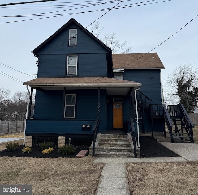 view of front facade featuring stairway, fence, covered porch, and roof with shingles