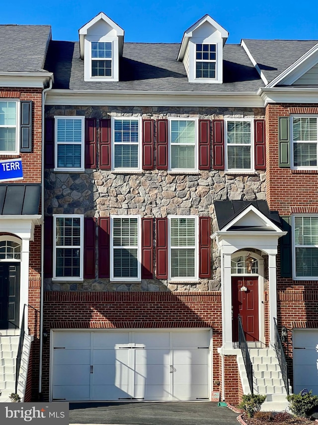 townhome / multi-family property featuring brick siding, a garage, and stone siding