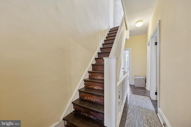 staircase with baseboards and wood finished floors