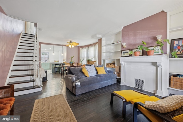 living area featuring visible vents, hardwood / wood-style flooring, a fireplace, ceiling fan, and stairs