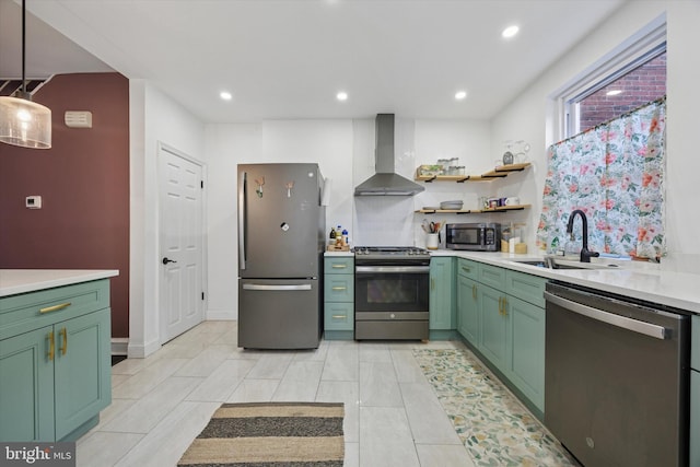 kitchen featuring a sink, stainless steel appliances, light countertops, green cabinets, and wall chimney range hood