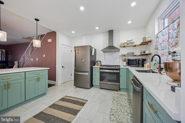 kitchen with a sink, green cabinets, appliances with stainless steel finishes, and wall chimney exhaust hood