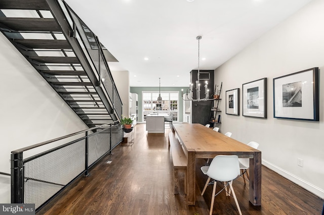 dining area featuring dark wood finished floors, a chandelier, stairs, and baseboards