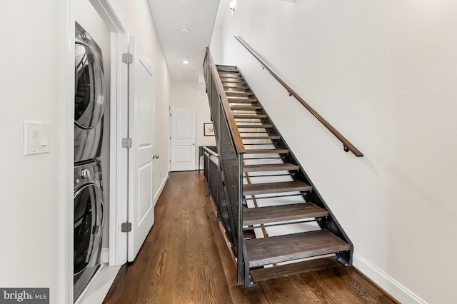 staircase featuring wood finished floors, baseboards, and stacked washing maching and dryer