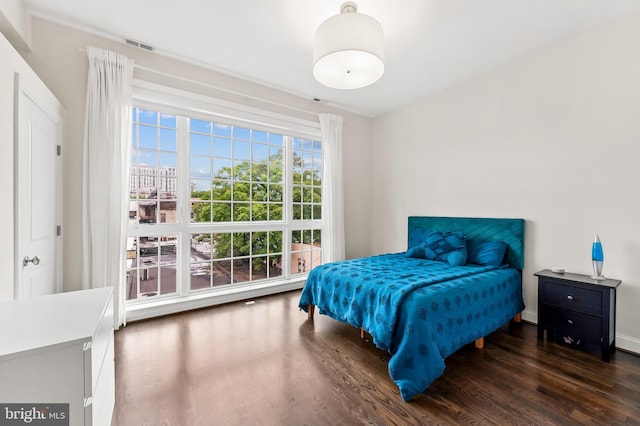 bedroom with visible vents, baseboards, and wood finished floors