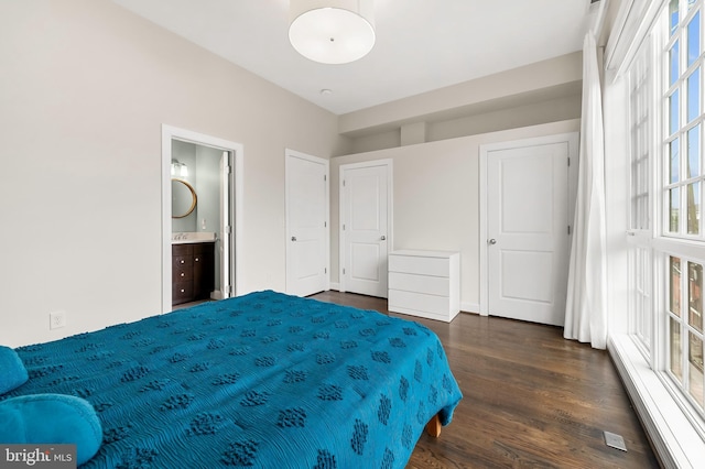 bedroom with dark wood finished floors, a baseboard radiator, and connected bathroom