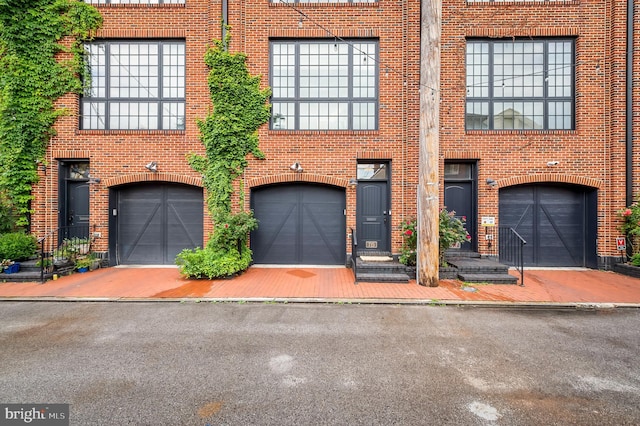 multi unit property featuring brick siding, driveway, and a garage