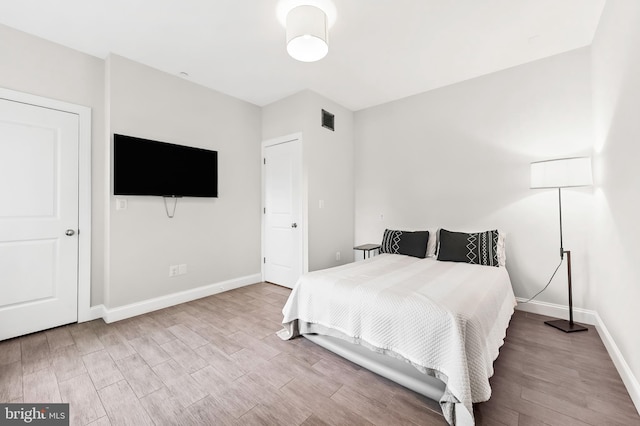 bedroom featuring visible vents, baseboards, and wood finished floors