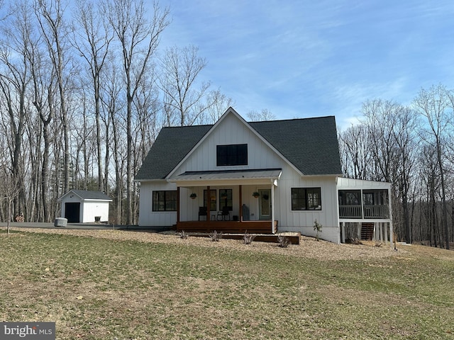 view of front of home with a shingled roof, covered porch, a garage, a sunroom, and an outdoor structure