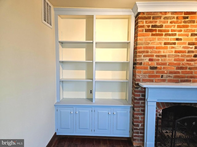 interior details with visible vents, a brick fireplace, and wood finished floors