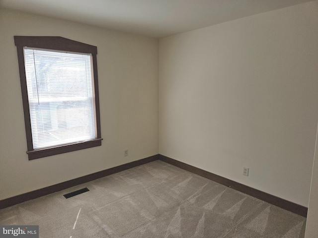 spare room featuring carpet flooring, baseboards, and visible vents