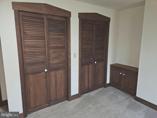 interior space with light carpet, two closets, and baseboards