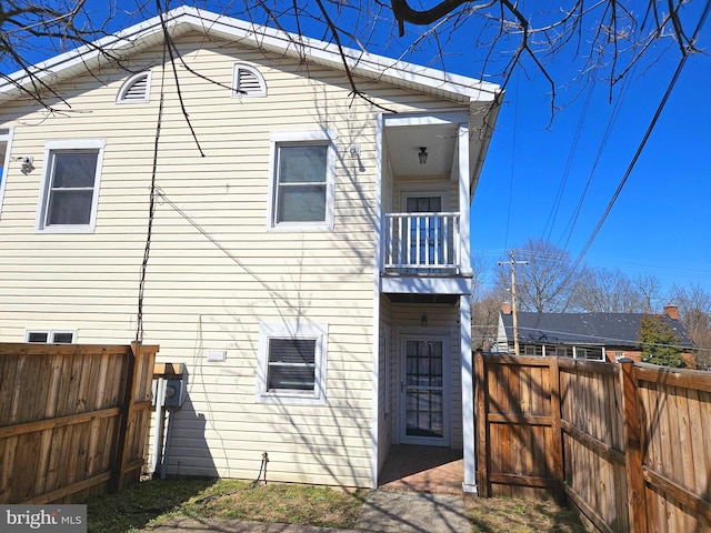 back of property featuring a balcony and fence