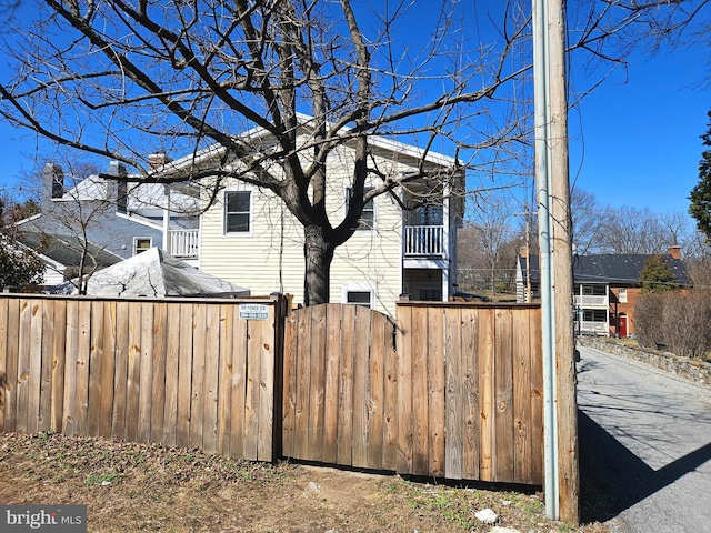 view of property exterior with a balcony, a gate, and fence