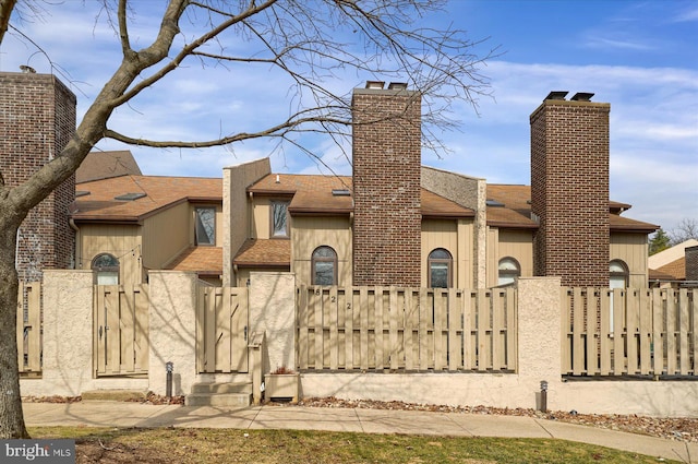 view of front of property featuring stucco siding, a gate, a fenced front yard, a shingled roof, and a chimney