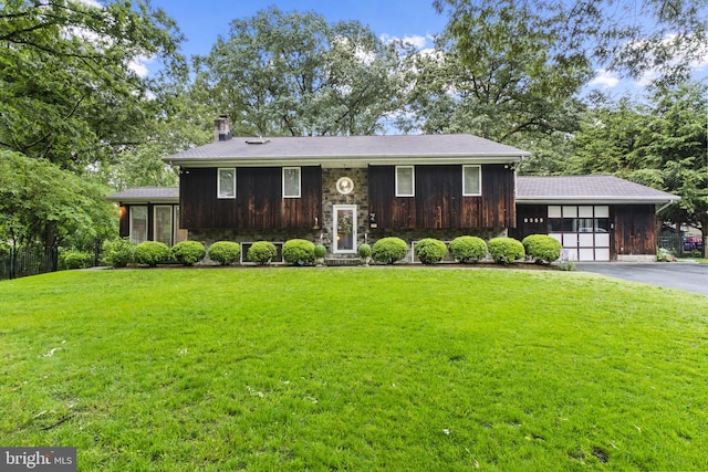 8359 Elm Rd, Millersville, MD 21108 - view of front facade featuring a chimney, a front yard, stone siding, asphalt driveway, and a garage