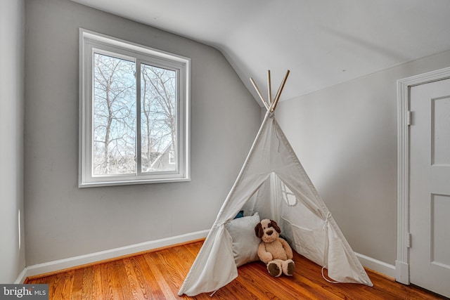 recreation room featuring lofted ceiling, baseboards, and wood finished floors