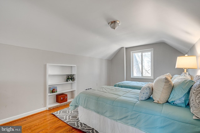 bedroom featuring baseboards, light wood-style floors, and vaulted ceiling