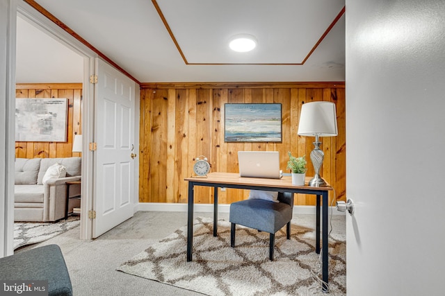 carpeted office space with baseboards and wooden walls