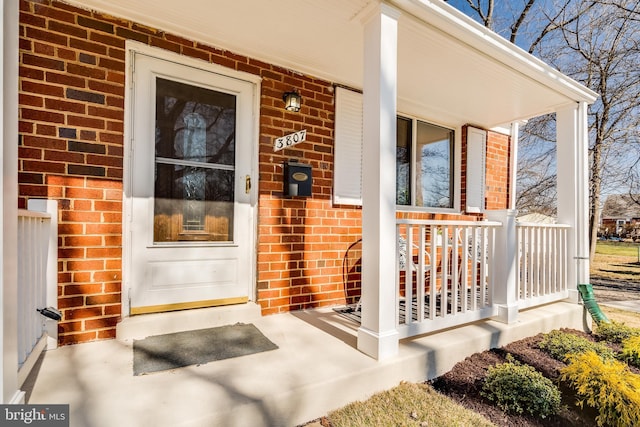 property entrance with brick siding and a porch