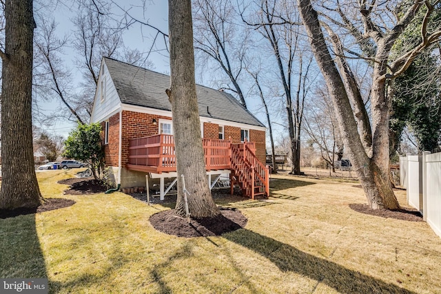 exterior space with a lawn, fence, stairway, a wooden deck, and brick siding