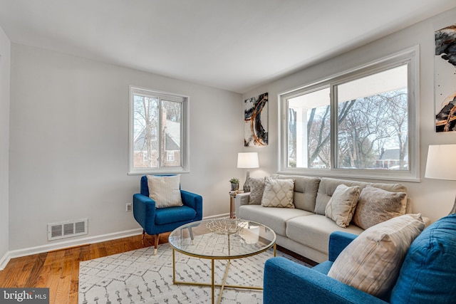 living room featuring a wealth of natural light, visible vents, baseboards, and wood finished floors