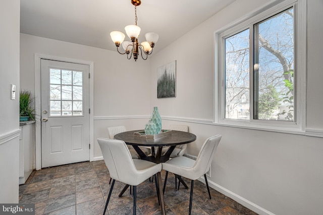 dining area with stone finish flooring, baseboards, and a chandelier