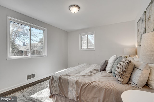 bedroom featuring wood finished floors, visible vents, and baseboards