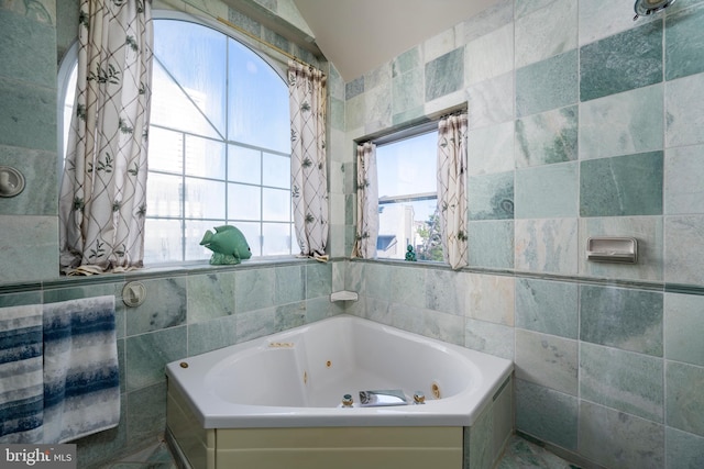 bathroom featuring a jetted tub and tile walls