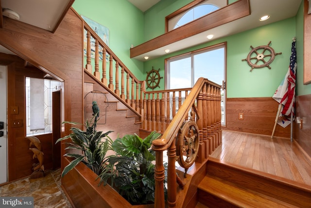 stairway featuring hardwood / wood-style floors, wooden walls, and a wainscoted wall