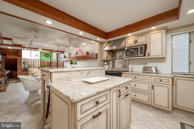 kitchen with cream cabinetry, electric stove, stainless steel microwave, wall chimney exhaust hood, and light tile patterned floors