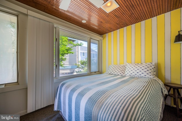 bedroom featuring wallpapered walls, wooden ceiling, and carpet