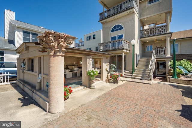 view of front facade featuring an outdoor kitchen, stairs, and a patio area