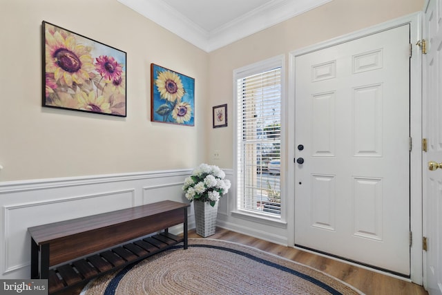 entrance foyer with a wainscoted wall, wood finished floors, and crown molding