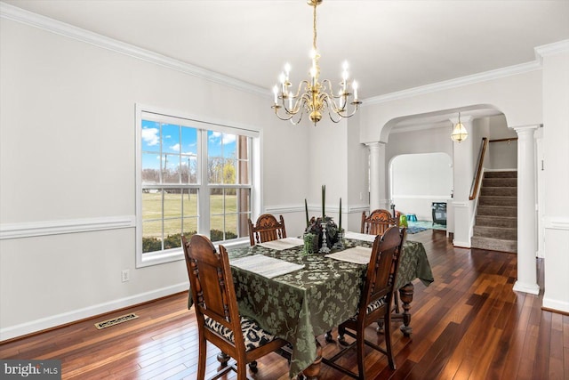 dining room with arched walkways, hardwood / wood-style flooring, crown molding, and decorative columns