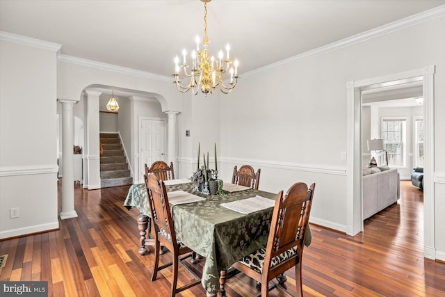 dining room with baseboards, stairway, ornamental molding, hardwood / wood-style flooring, and arched walkways