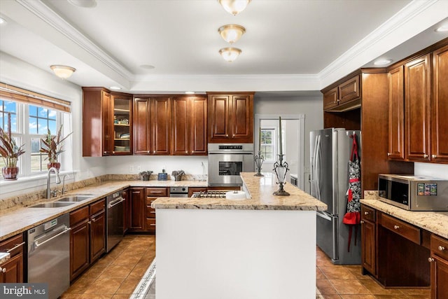 kitchen with a healthy amount of sunlight, appliances with stainless steel finishes, a kitchen island, and a sink