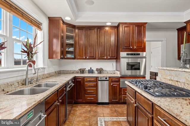 kitchen featuring crown molding, light stone countertops, appliances with stainless steel finishes, and a sink