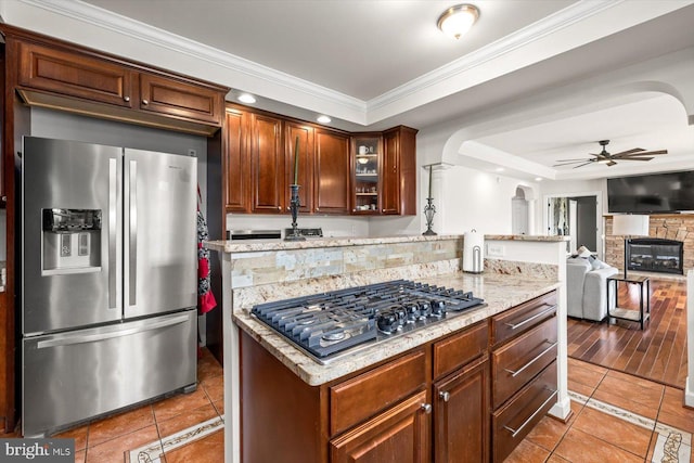 kitchen with ceiling fan, light stone countertops, ornamental molding, light tile patterned floors, and appliances with stainless steel finishes