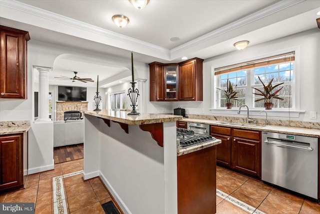 kitchen with a ceiling fan, ornate columns, a tray ceiling, a sink, and stainless steel dishwasher