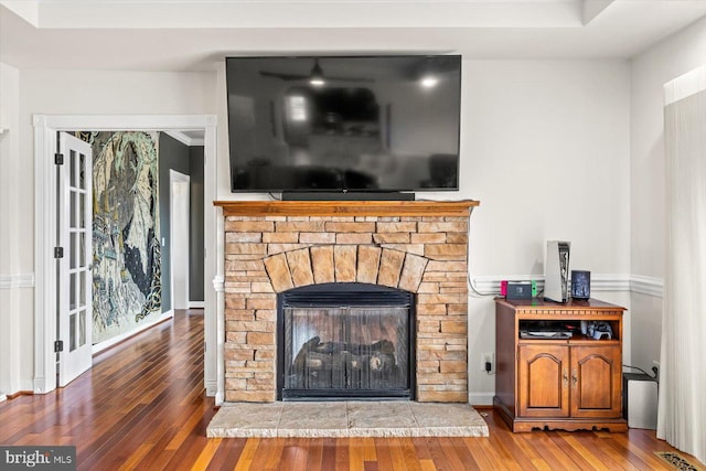 room details with a stone fireplace, wood finished floors, and visible vents