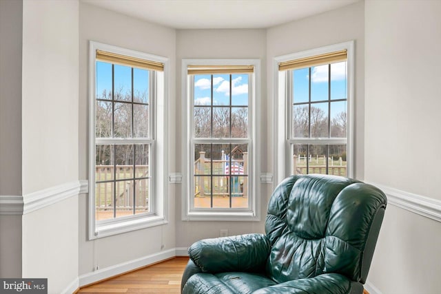 living area with baseboards and wood finished floors