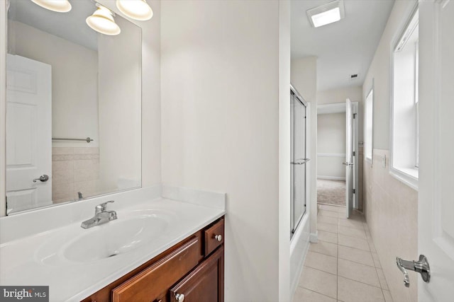 bathroom with a shower with door, plenty of natural light, tile patterned floors, and vanity