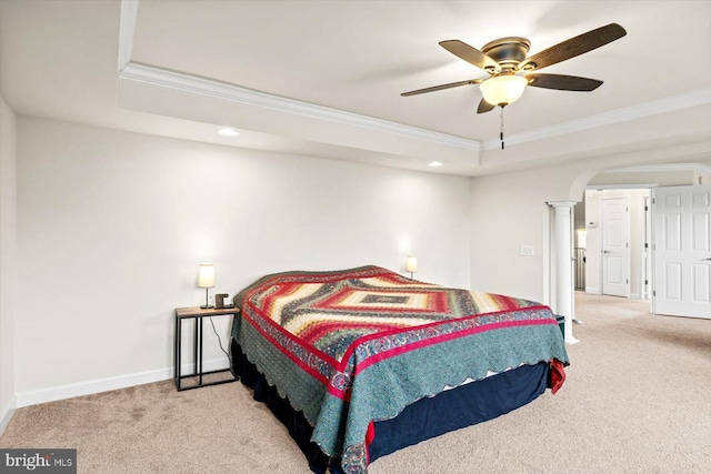 carpeted bedroom featuring a raised ceiling, crown molding, arched walkways, and baseboards