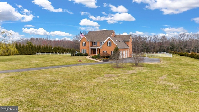 view of front of house featuring a front yard, fence, a forest view, a garage, and aphalt driveway