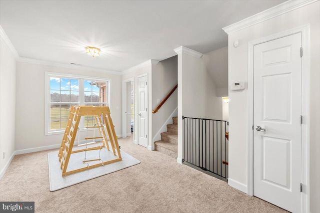 interior space featuring an upstairs landing, carpet flooring, baseboards, and ornamental molding