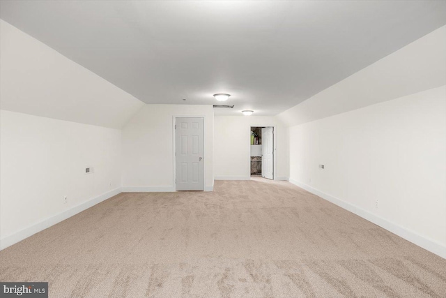 additional living space featuring baseboards, light carpet, and lofted ceiling