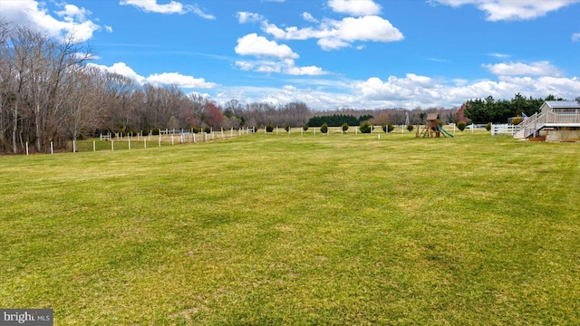 view of yard with a rural view, a playground, and fence