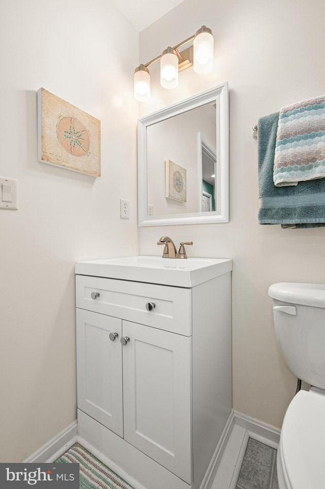 bathroom featuring toilet, vanity, and baseboards