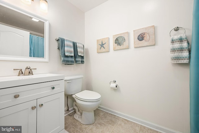 bathroom with baseboards, toilet, vanity, and tile patterned flooring